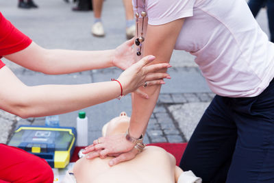 Midsection of female paramedic performing cpr on dummy