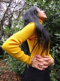 Midsection of woman standing by tree