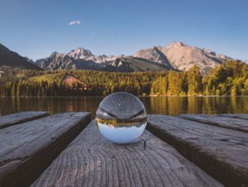 Wooden post in lake by mountains against sky