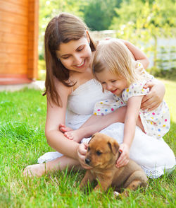 Mother and daughter playing with dog on grass