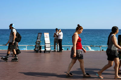 Women standing at beach against clear sky