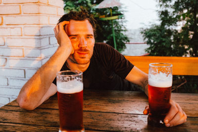 Midsection of man drinking glass on table