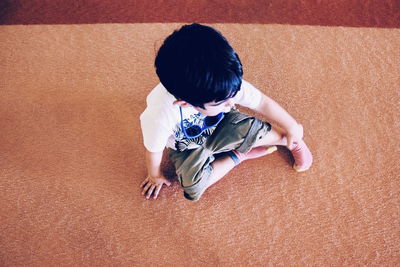 High angle view of boy sitting on carpet at home