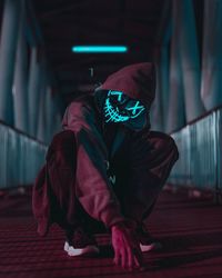 Young man in mask crouching under tunnel at night