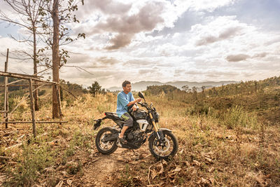 Man looking away while sitting on motorcycle against sky