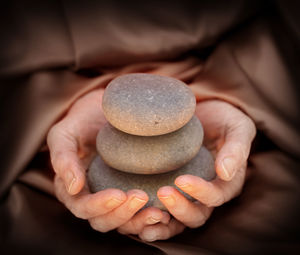 Cropped hands holding stacked pebbles