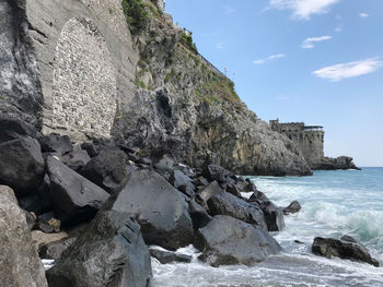 Rock formation on beach against sky