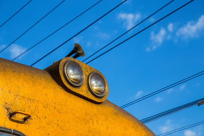 Low angle view of yellow cable car against sky