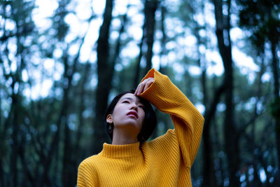 Low angle view of woman looking up in forest