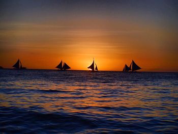 Silhouette sailboat sailing on sea against sky during sunset