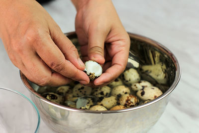 Asian old woman hand peel quail egg on stainless bowl. cooking process in the kitchen