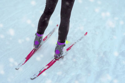 Low section of woman skiing on snow during snowfall