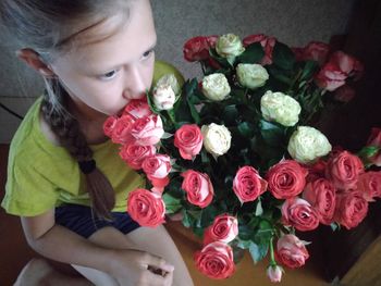 High angle view of girl smelling flowers at home