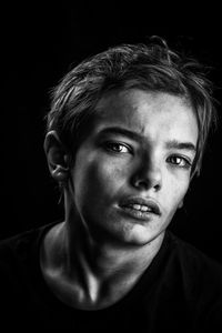 Close-up portrait of young woman against black background