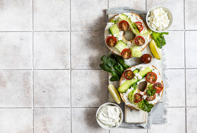 Bagels sandwich with cream cheese, cottage cheese, avocado, tomatoes, cucumbers and salad leaves