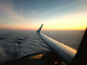 Close-up of airplane flying over sea against sky during sunset