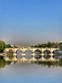 Arch bridge over river against blue sky