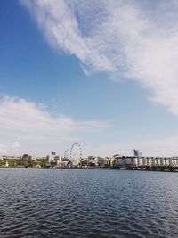 View of buildings by river against cloudy sky