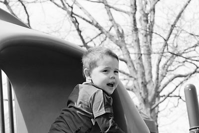 Cute boy playing at jungle gym against sky