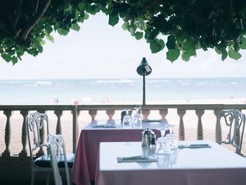 Empty chairs and tables at restaurant by sea