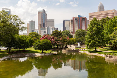 Lake and buildings in park against sky