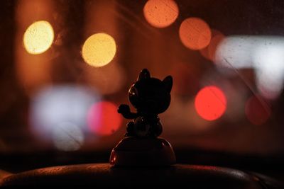 Close-up of silhouette kitten figurine against multi colored defocused background