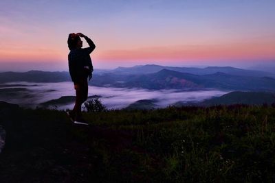 Full length of man standing on mountain against sky during sunset