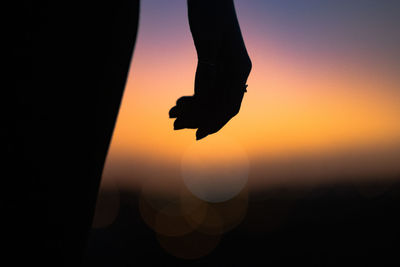 Low section of silhouette person standing against sky during sunset
