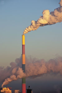 Smoke stack against sky at sunset