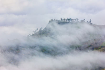Aerial view of clouds covering mountain against sky