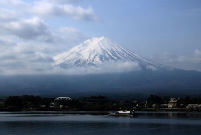 Scenic view of river and snowcapped mountains against sky during foggy weather