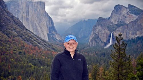 Portrait of smiling woman standing on mountain against sky