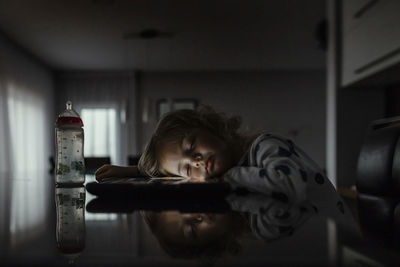 Cute baby girl sleeping by tablet computer on table at home