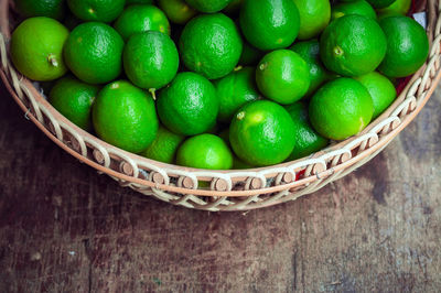 High angle view of green lemons in container on table