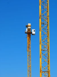 Low angle view of crane against clear blue sky