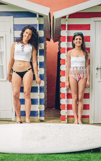 Portrait of smiling friends standing against beach hut