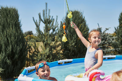 Children playing in a pool with fishing rod toy in a home garden. kids having fun playing together 