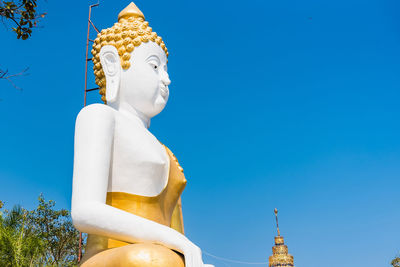 Low angle view of statue against building against blue sky