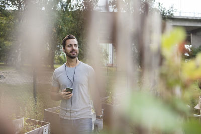 Mid adult man using mobile phone in community garden