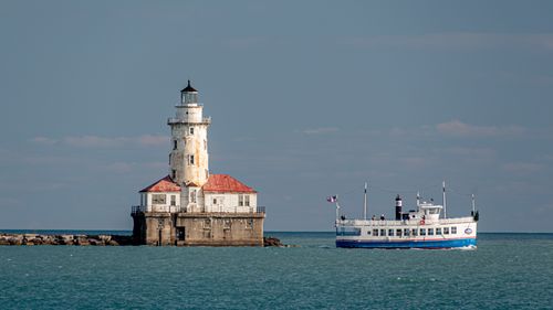 Lighthouse by sea against clear sky