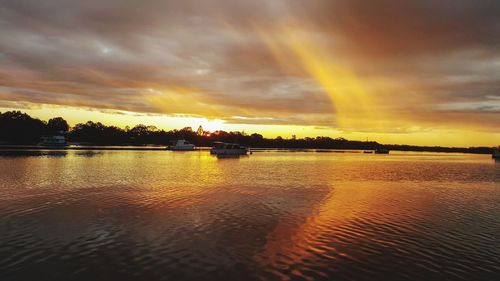 Scenic view of lake against dramatic sky during sunset