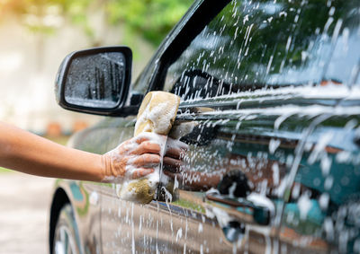 Woman hands hold sponge for washing car at home. car detailing concept.