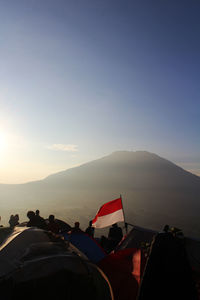 People on beach against sky during sunset