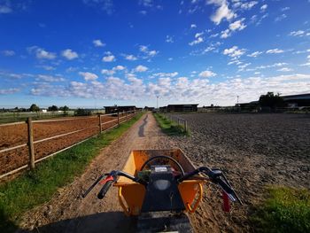 Road amidst agricultural field against sky