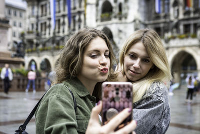 Close-up of young woman taking selfie with female friend in city