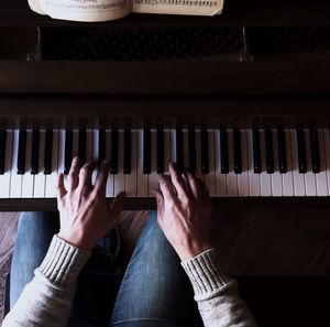 Cropped image of person hand playing piano