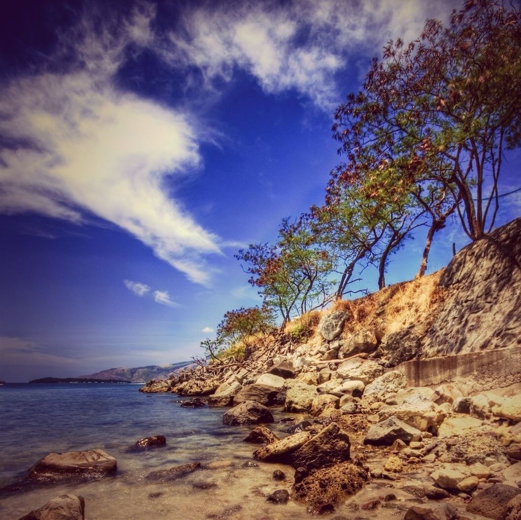 sky, tranquility, tranquil scene, sea, scenics, water, beauty in nature, beach, nature, tree, rock - object, shore, cloud - sky, cloud, rock formation, sand, idyllic, horizon over water, rock, blue