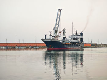 Cranes at harbor against sky