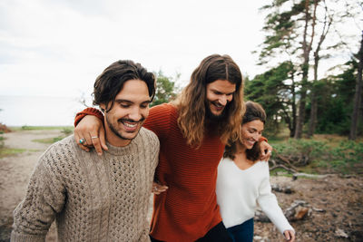 Smiling friends walking with arms around outdoors