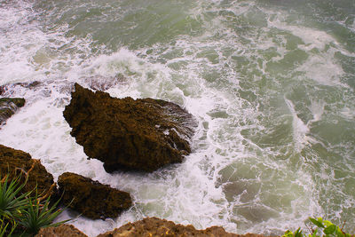 High angle view of waves splashing on rocks at shore
